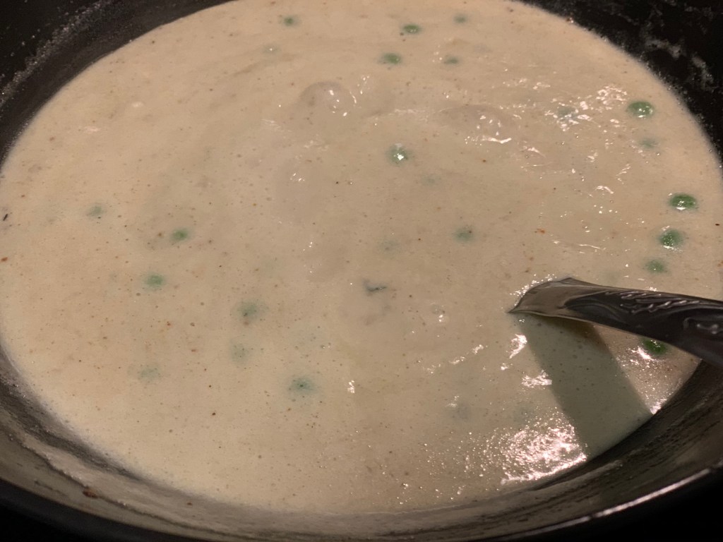 Fine paste, garam masala, and green peas cooking in the ghee.